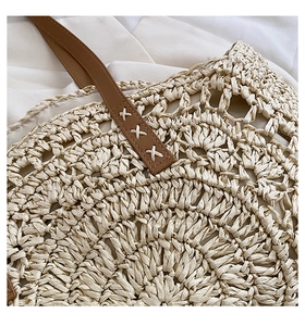 Detailed close-up of woven straw handbag featuring hollow patterns and leather handles