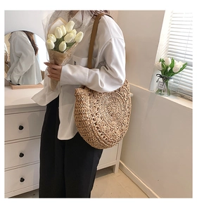 Close-up of circular straw shoulder bag showing detailed spiral woven texture and leather strap