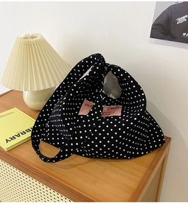Detailed macro shot of a black polka dot canvas tote bag with pink logo patch