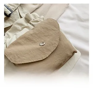 Close-up of khaki nylon flap bag with silver magnetic snap and neat stitching