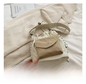 Detail view of cream oxford bucket bag with drawstring closure and khaki pocket on front