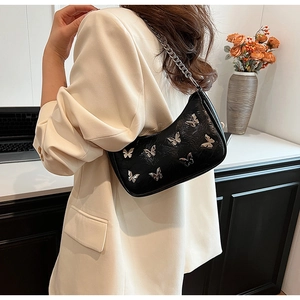 Détail du sac bandoulière en cuir PU noir avec breloques papillons et grosse chaîne argent