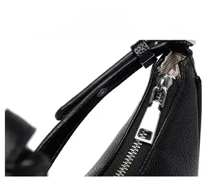 Detail of smooth silver zipper and pebbled black leather on minimalist underarm bag
