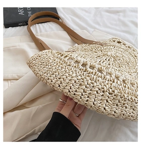 Detailed view of the handcrafted straw tote bag with brown faux leather handles and stitching