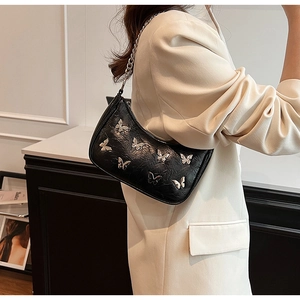 Détail du sac bandoulière en cuir PU noir avec breloques papillon argentées sur le mannequin