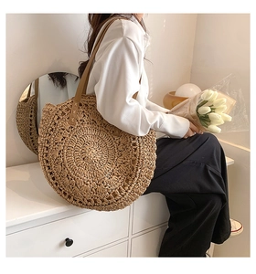 Detail of the woven straw shoulder bag featuring intricate crochet texture and leather strap