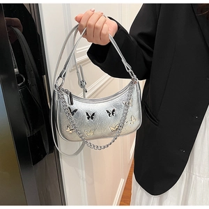 Détail du sac demi-lune argenté avec patchs papillon et bandoulière en chaîne métal