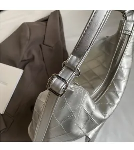Detail of silver quilted crossbody bag with adjustable metallic strap and buckle closure