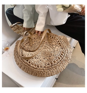Close-up of brown leather handles with cross-stitch detail on large straw handbag