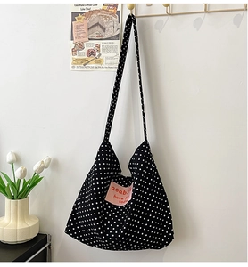 Detailed close-up of retro black polka dot canvas bag with pink 'aoab' letter patch