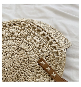 Detail of hand-woven straw bag texture with brown leather strap and white cross-stitching