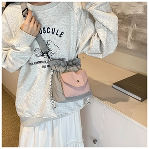 Close-up of gray nylon drawstring crossbody bag with a pink snap pocket and striped rope