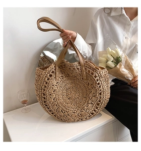 Macro detail of the woven straw texture and premium brown leather handle on this summer tote