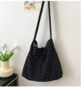 Detailed view of large canvas crossbody bag with classic black and white polka dot pattern