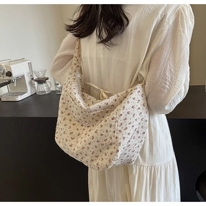Detail of floral canvas crossbody bag featuring bow tie strap and zipper closure