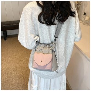 Detail of grey Oxford cloth crossbody bag with pink flap pocket shown on a model