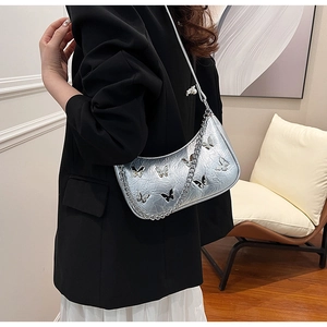 Détail du sac argenté en similicuir plissé avec ornements papillon 3D et chaîne en métal