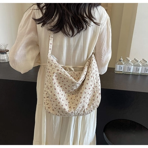 Detailed back view of a floral canvas crossbody bag on a model showing size and fit