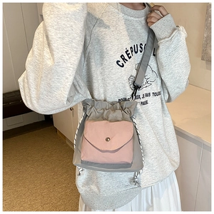 Detail view of Oxford cloth crossbody bag with grey body and pink drawstring front pocket