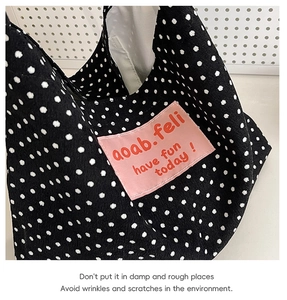 Close-up of black and white polka dot canvas bag with pink 'have fun today' brand label