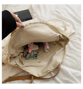 Interior view of round straw tote showing large capacity with zipper pocket and lining