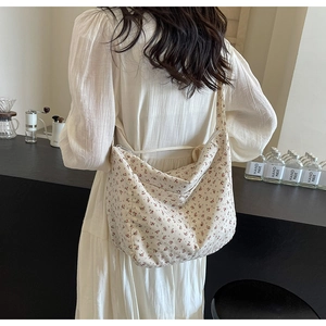 Detailed view of beige floral canvas hobo bag worn by a model in a casual setting