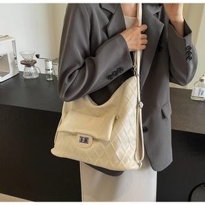Close-up of cream PU leather shoulder bag with quilted diamond pattern and rotating metal buckle