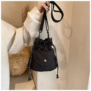 Close-up of black nylon bucket bag with drawstring closure and silver metal snap button