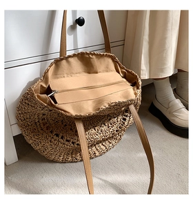 Detail showing handwoven straw texture and interior zippered pocket with lining