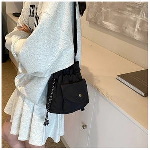Detail of black nylon drawstring bucket bag with textured woven cord and metal buckle