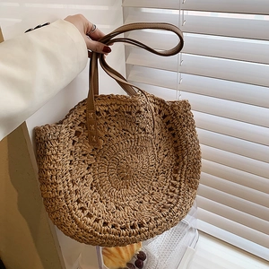 Large circular straw tote bag with brown leather shoulder straps for summer beach vacations