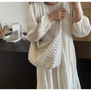 Detailed close-up of blue floral cotton crossbody bag with minimalist half-moon design
