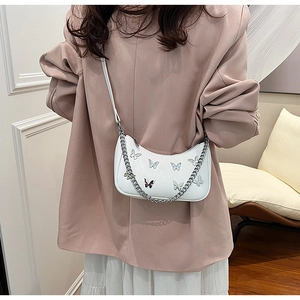 Détail de charmes papillon argentés et chaîne sur sac hobo blanc en forme de lune