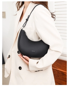 Detail of black lychee grain leather crescent bag featuring silver STLY logo and zipper