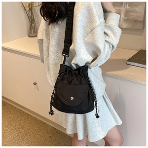 Close-up of black nylon bucket bag featuring a flap pocket and woven drawstrings
