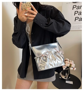 Detail of silver metallic PU crossbody bag featuring pleated design and pink bows decoration