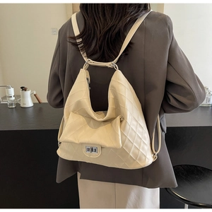 Detail of beige quilted PU leather backpack featuring silver twist lock and hobo style