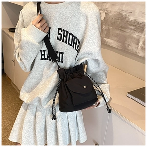 Detail of black oxford drawstring bucket bag with silver snap button front pocket