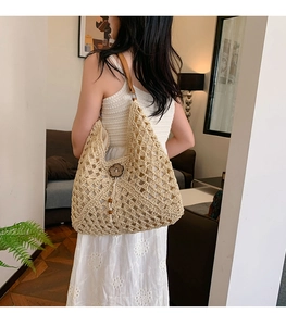 Macro shot of boho straw woven shoulder bag with floral wood charm and leather strap