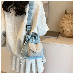 Detail of light blue nylon bucket bag with gray magnetic pocket and drawstring closure
