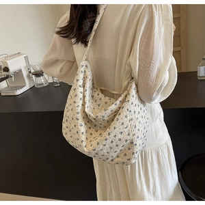 Detailed view of the floral canvas crossbody bag with small blue flowers and zipper