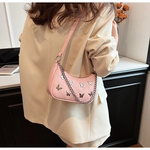 Détail du sac demi-lune rose avec clous papillon en métal et une chaîne décorative en argent