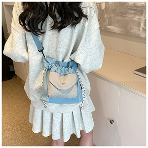Detail of blue-grey nylon crossbody bag with drawstring closure and front flap pocket