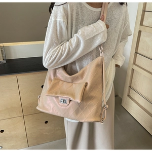 Detail of pearlescent beige quilted tote bag with silver metal twist-lock and shoulder strap