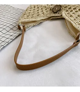 Close-up of woven straw shoulder bag with brown leather strap and wood flower buckle