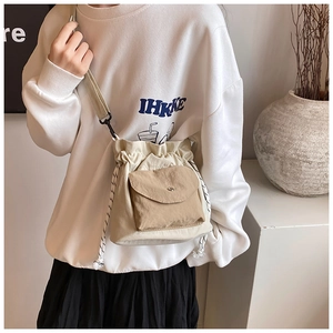 Detail of cream drawstring bucket bag with khaki pocket and woven shoulder strap
