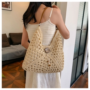 Detail of hand-woven straw shoulder bag featuring a unique wooden petal clasp and leather strap
