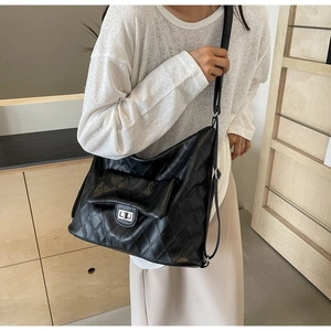 Detailed view of black quilted PU leather shoulder bag with silver turn-lock and adjustable strap