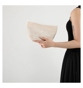 Close-up of beige woven fiber texture and white zipper on crescent handbag