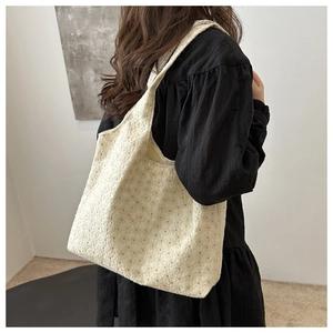 Detailed texture of white plush tote bag with star patterns on a stylish shoulder strap